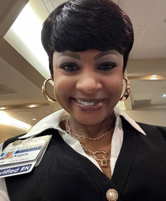 Smiling retail worker in black vest and white shirt, wearing a name badge and gold jewelry under store lighting