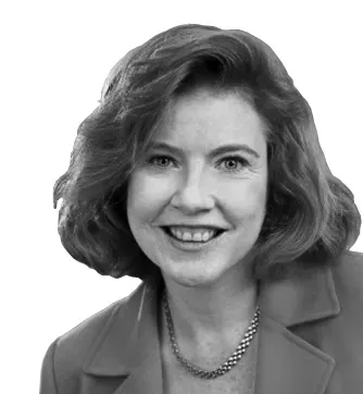 Black-and-white headshot of a smiling woman in a blazer and necklace