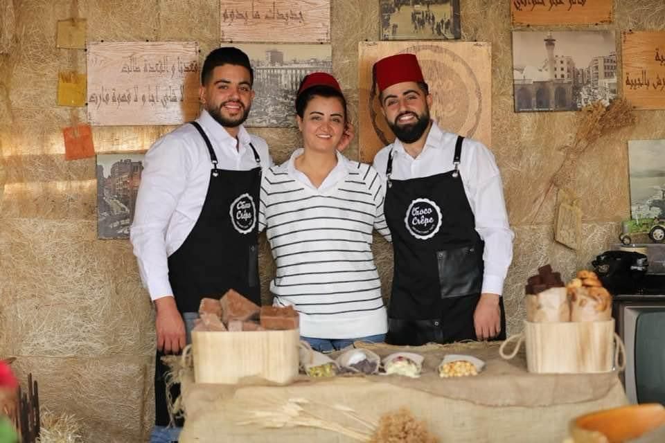 Three men and a woman are posing for a picture in front of a table.