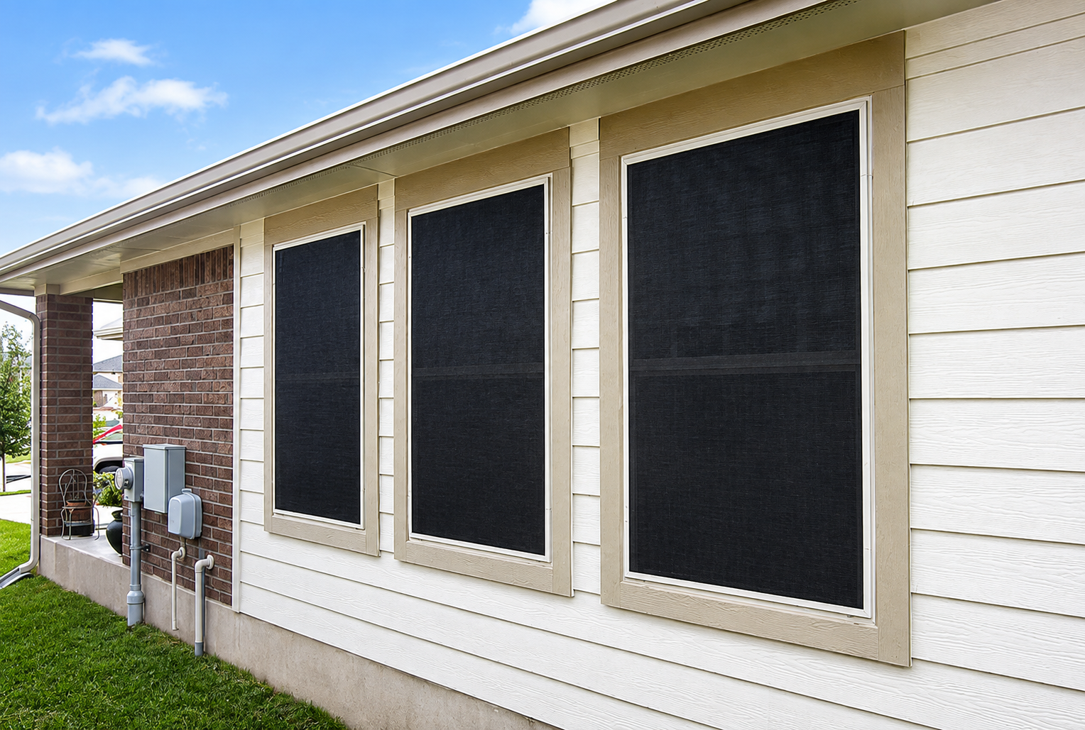 Exterior of a house with three dark screened windows and beige siding under a sloped roof