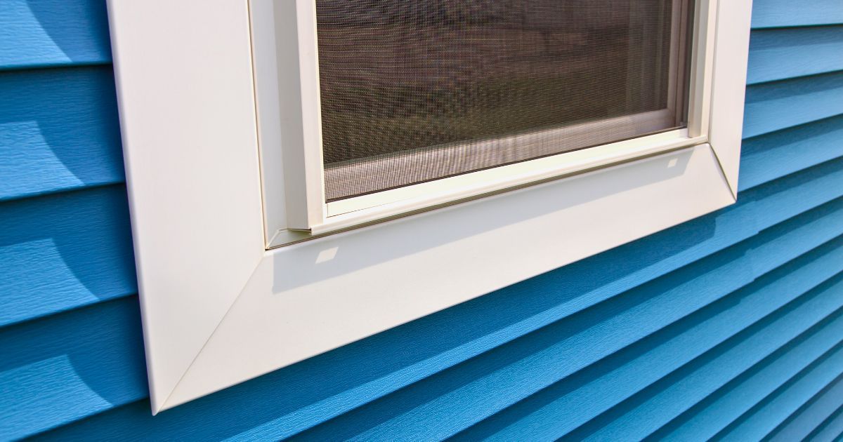 Close-up of a white-trimmed window on bright blue siding