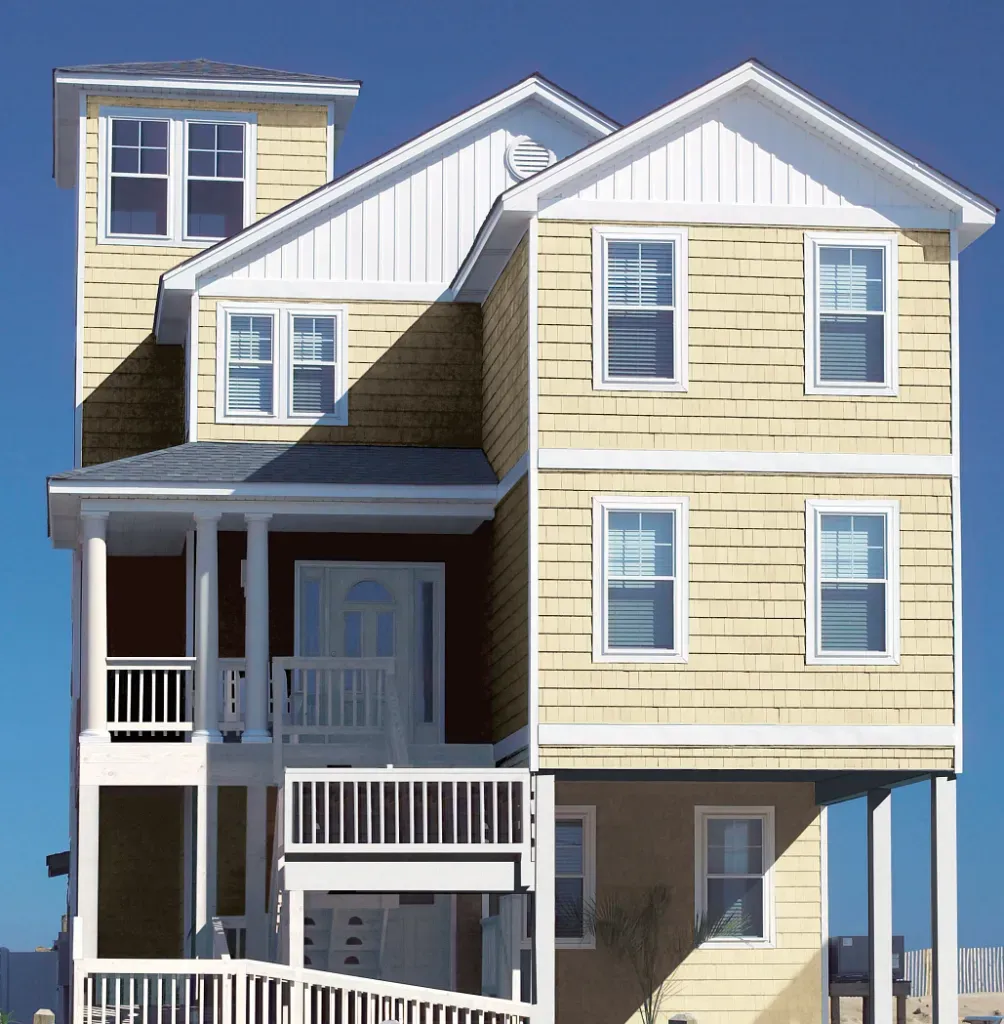 Multi-story yellow house with white trim, porches, and balconies under a clear blue sky