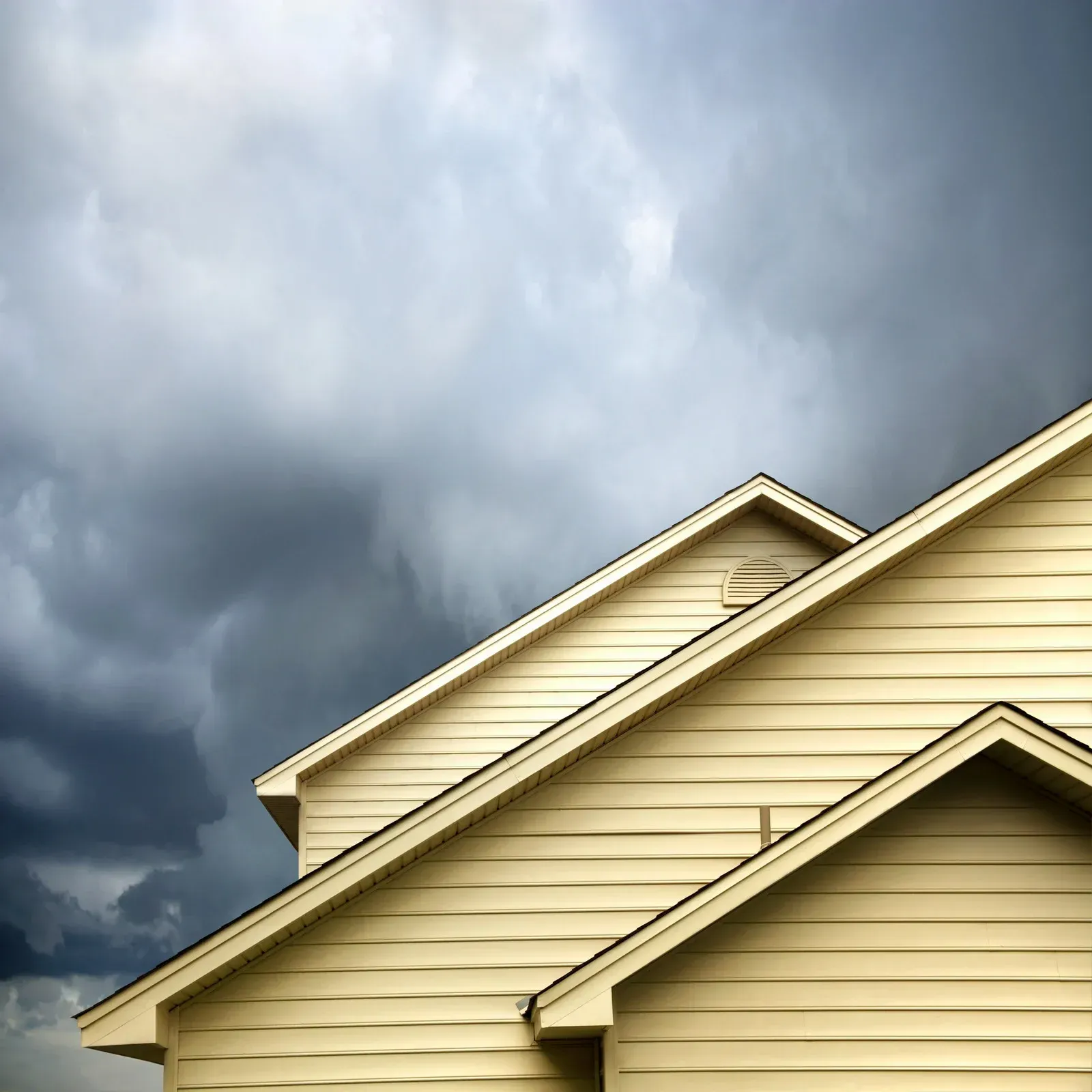 Person pointing at a vent on a green house exterior under the eaves