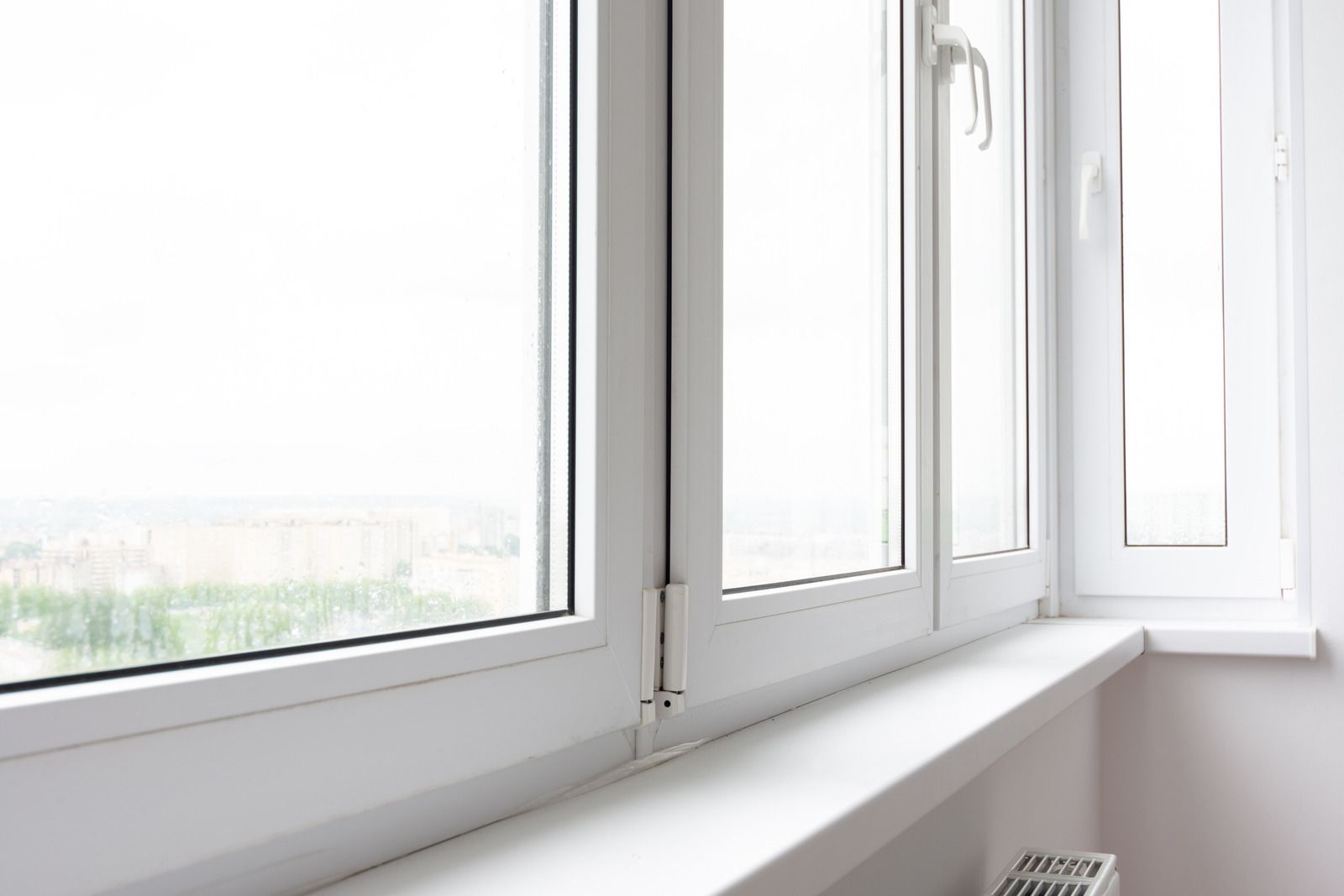 White windowsill with open white-framed windows in a bright, minimalist room