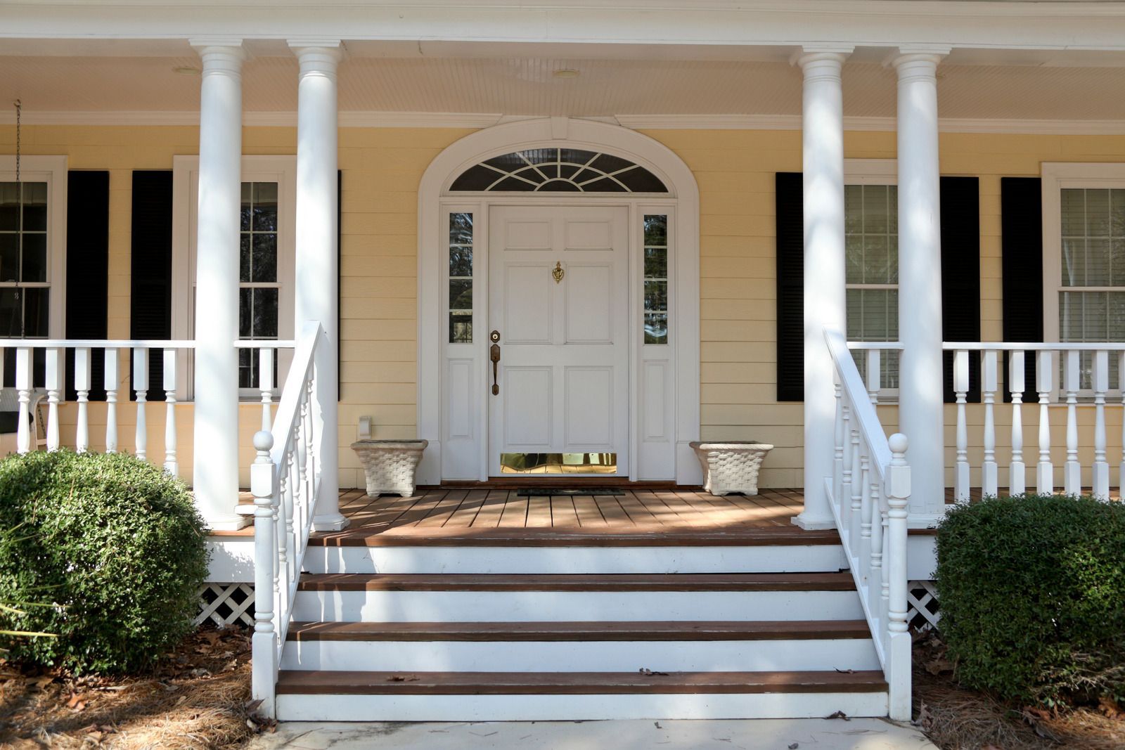 Front porch with white columns, steps, and a centered white front door with black shutters