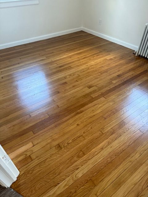 Wooden floor with a polished, glossy finish in a room with white walls.