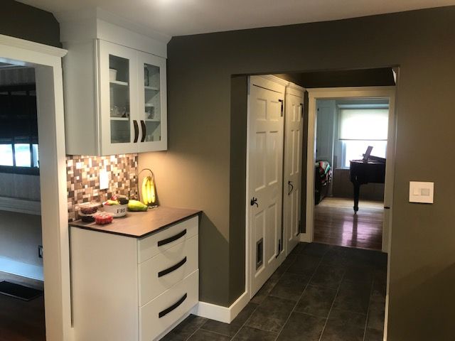 Kitchen with white cabinets, brown countertops, and dark gray tiled floor leading to a hallway.