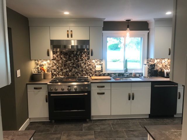 Kitchen with light gray cabinets, black appliances, stone backsplash, and dark gray flooring.
