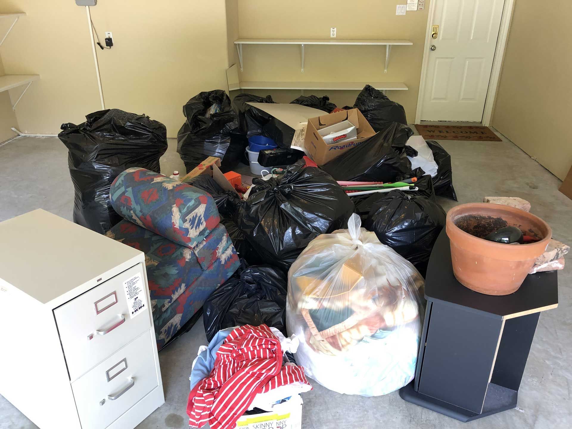 room with a pile of old furniture and junk items inside black garbage bags