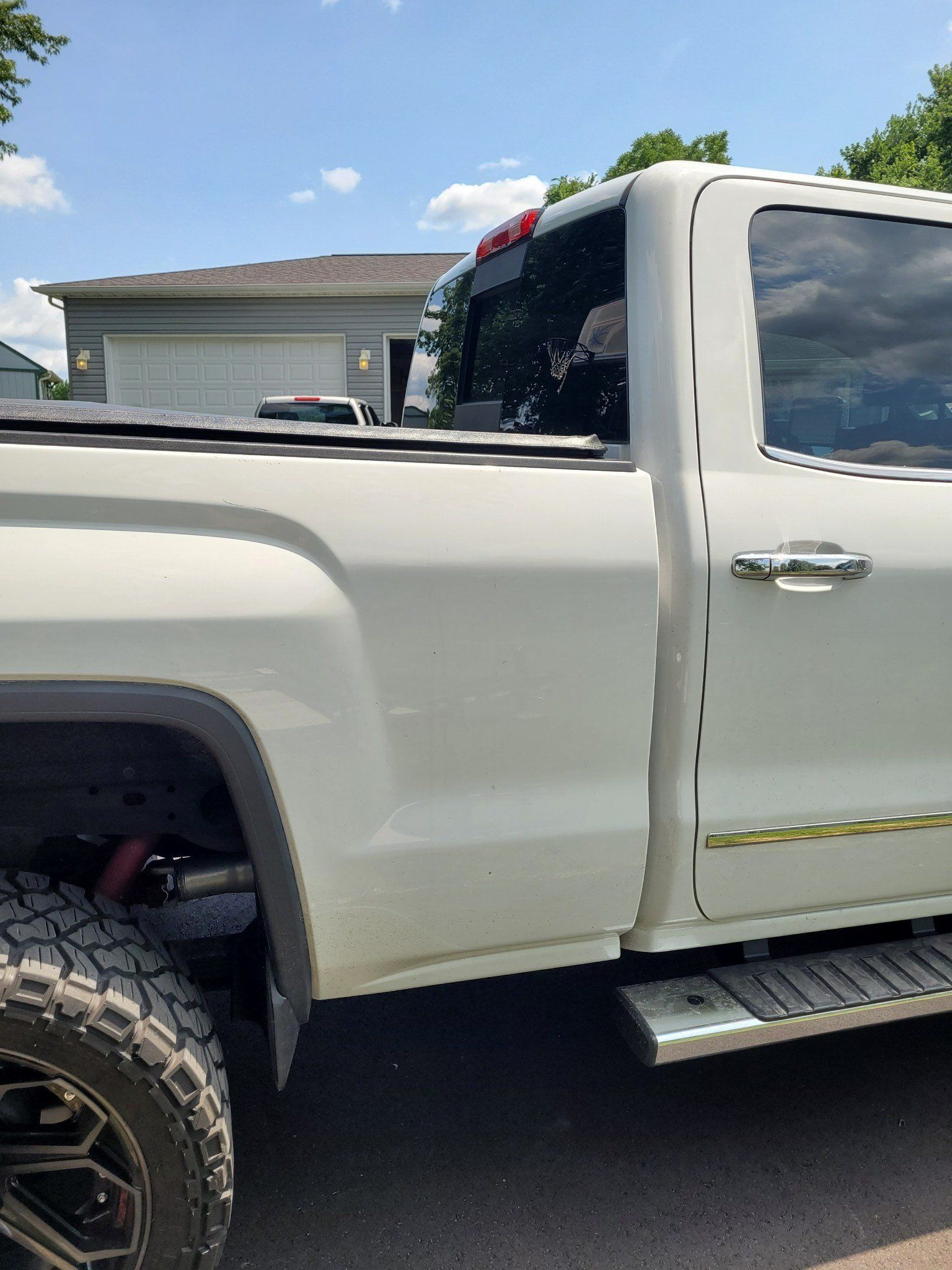 White pickup truck parked in a driveway beside a house, side view