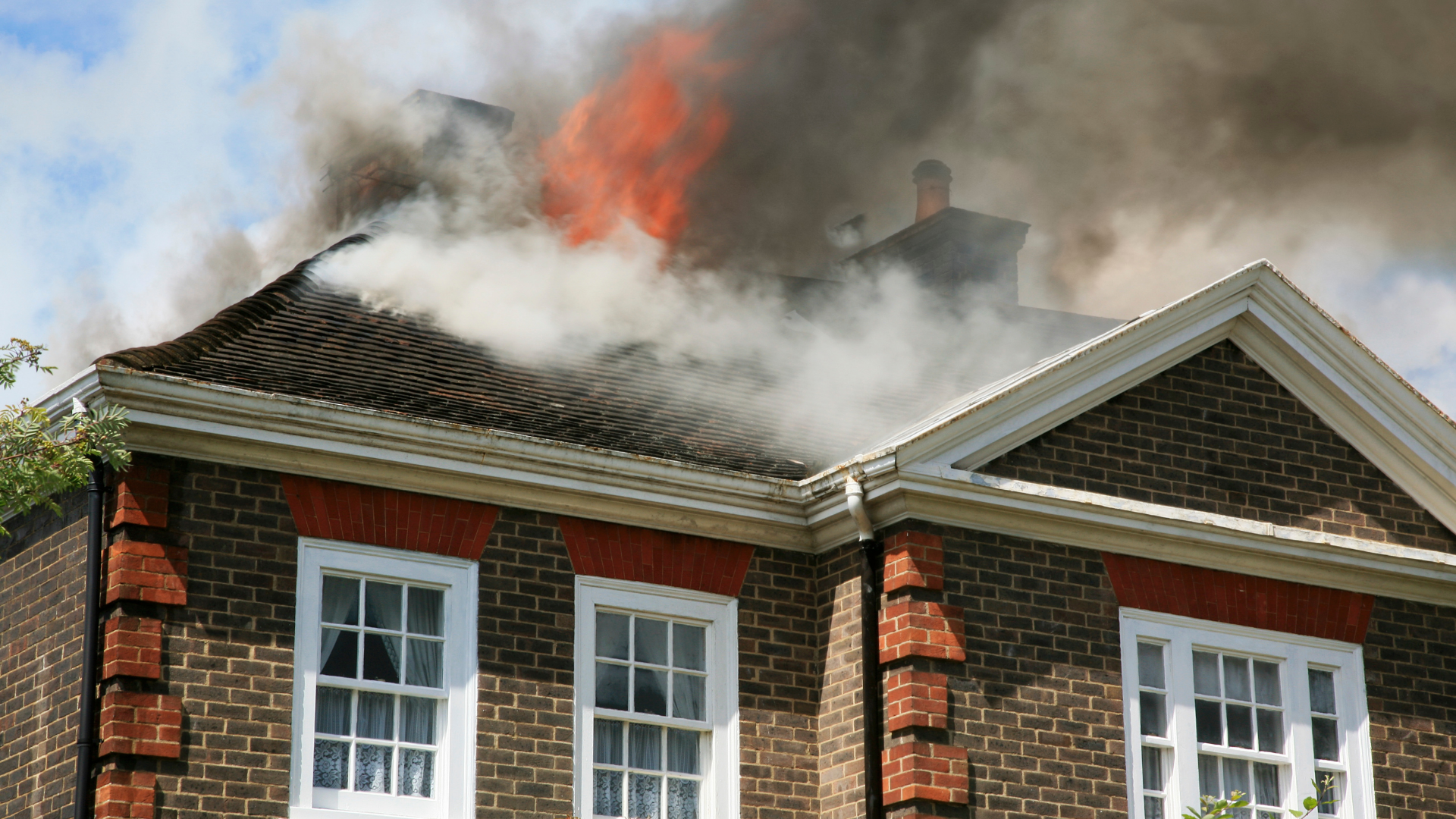 House on fire; smoke and flames erupt from the roof.