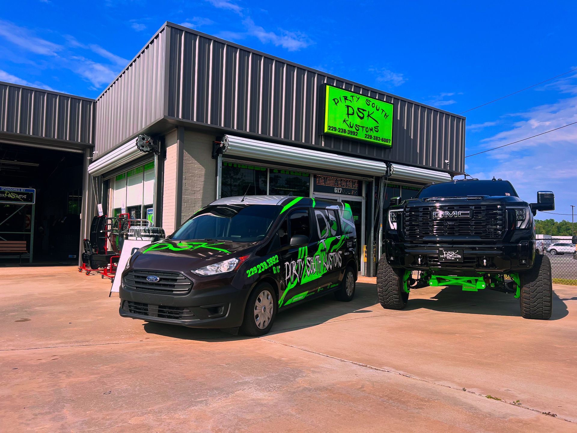 Dirty South Kustoms' branded cars outside of the shop.