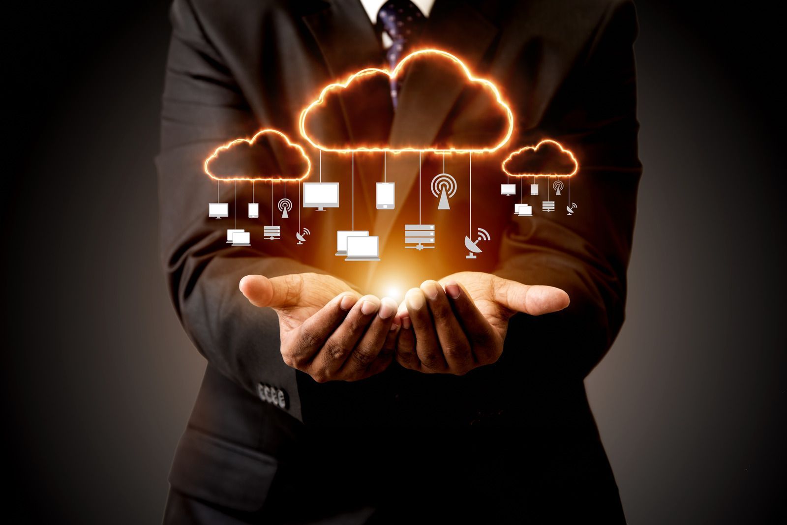 Hands cupping glowing cloud and digital icons against a dark background