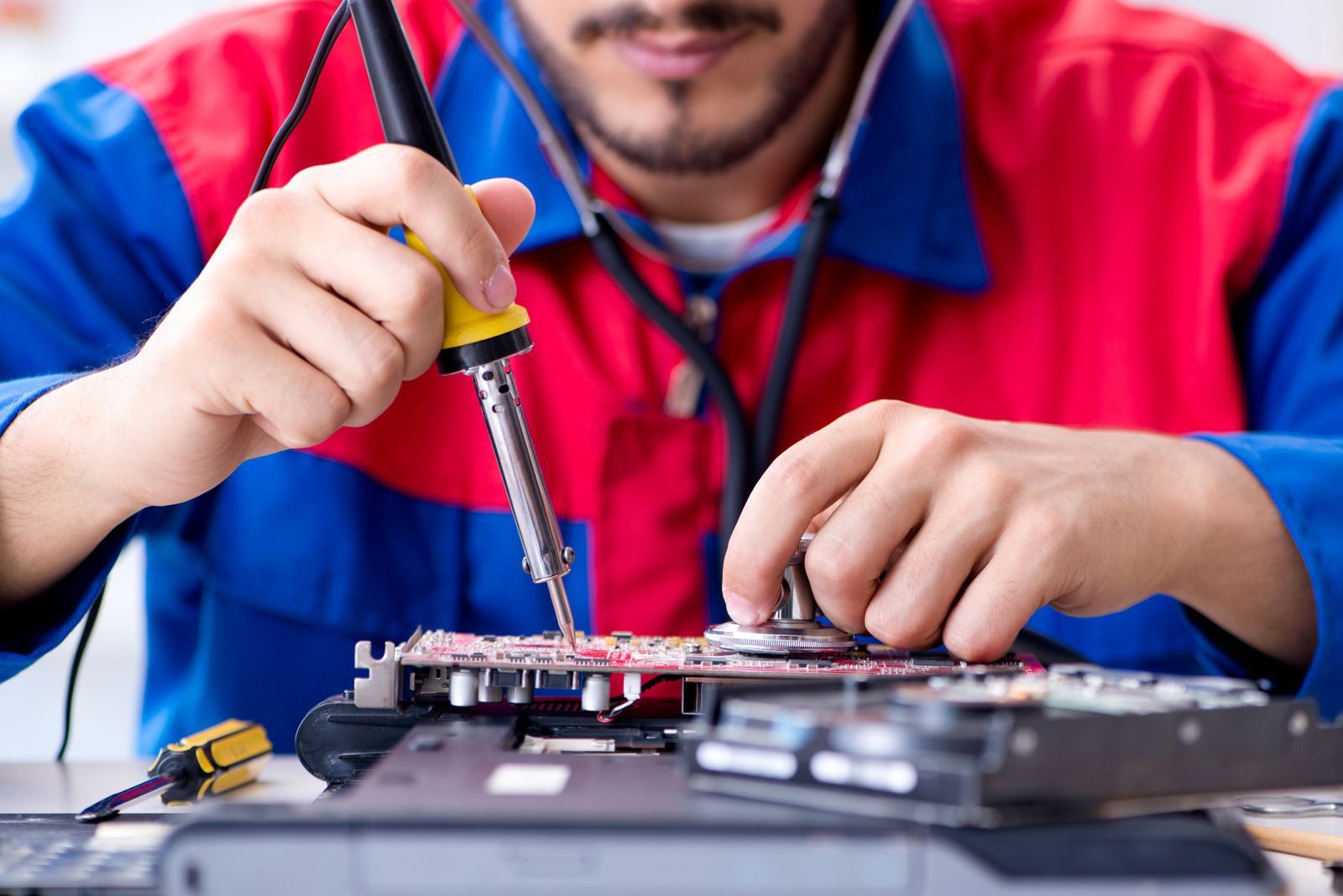 Technician soldering a circuit board with a soldering iron on a workbench