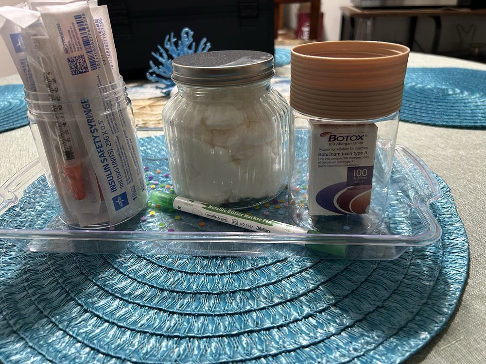 Glass tray with a jar and two cylindrical containers on a blue placemat in sunlight