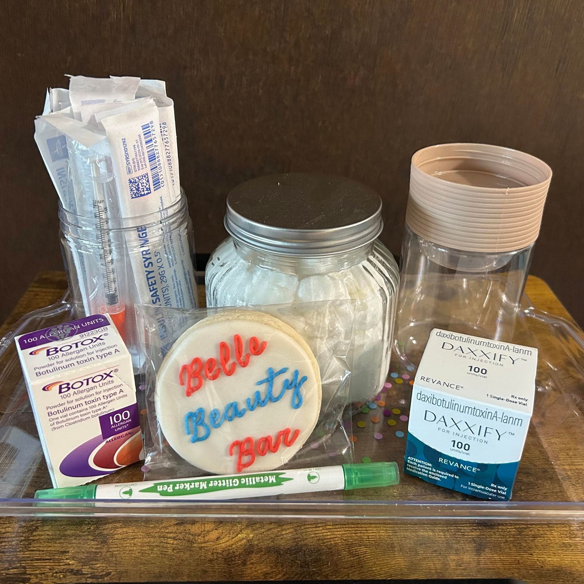 Assorted personal care items and containers arranged on a tray against a dark background.