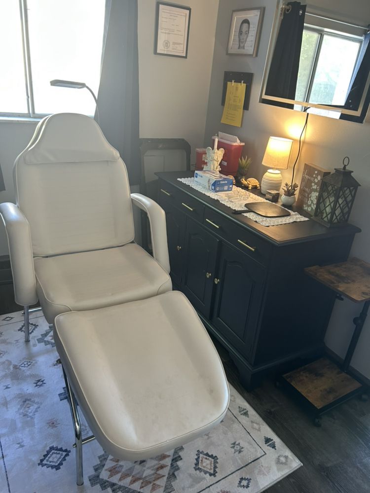 White reclining treatment chair in a dimly lit spa or salon room with a vanity and lamp.
