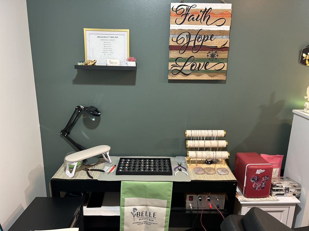 Home office desk with printer, lamp, keyboard, wall art, and shelves on a dark green wall