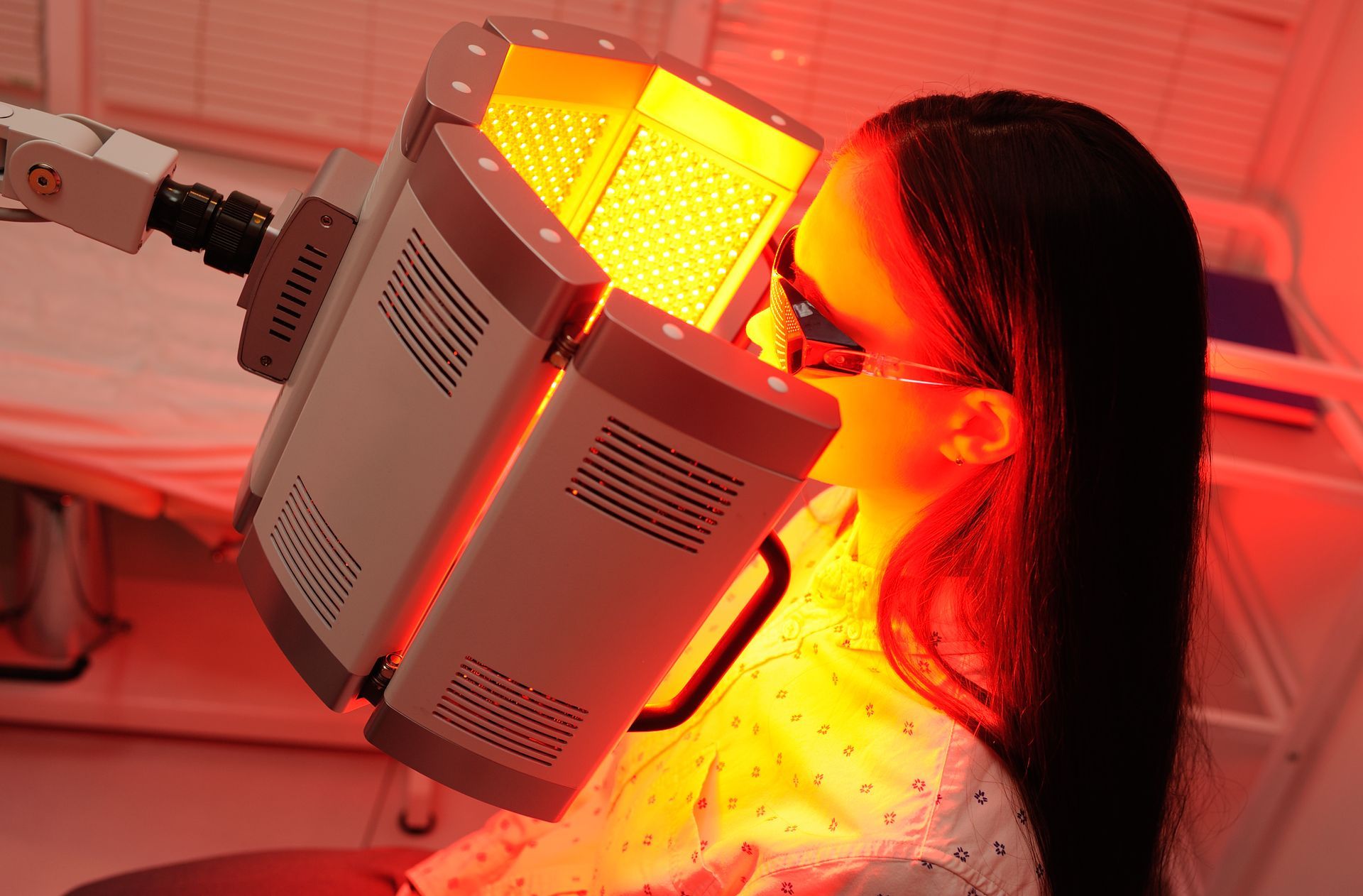 Woman receiving red light therapy from a medical device in a clinic