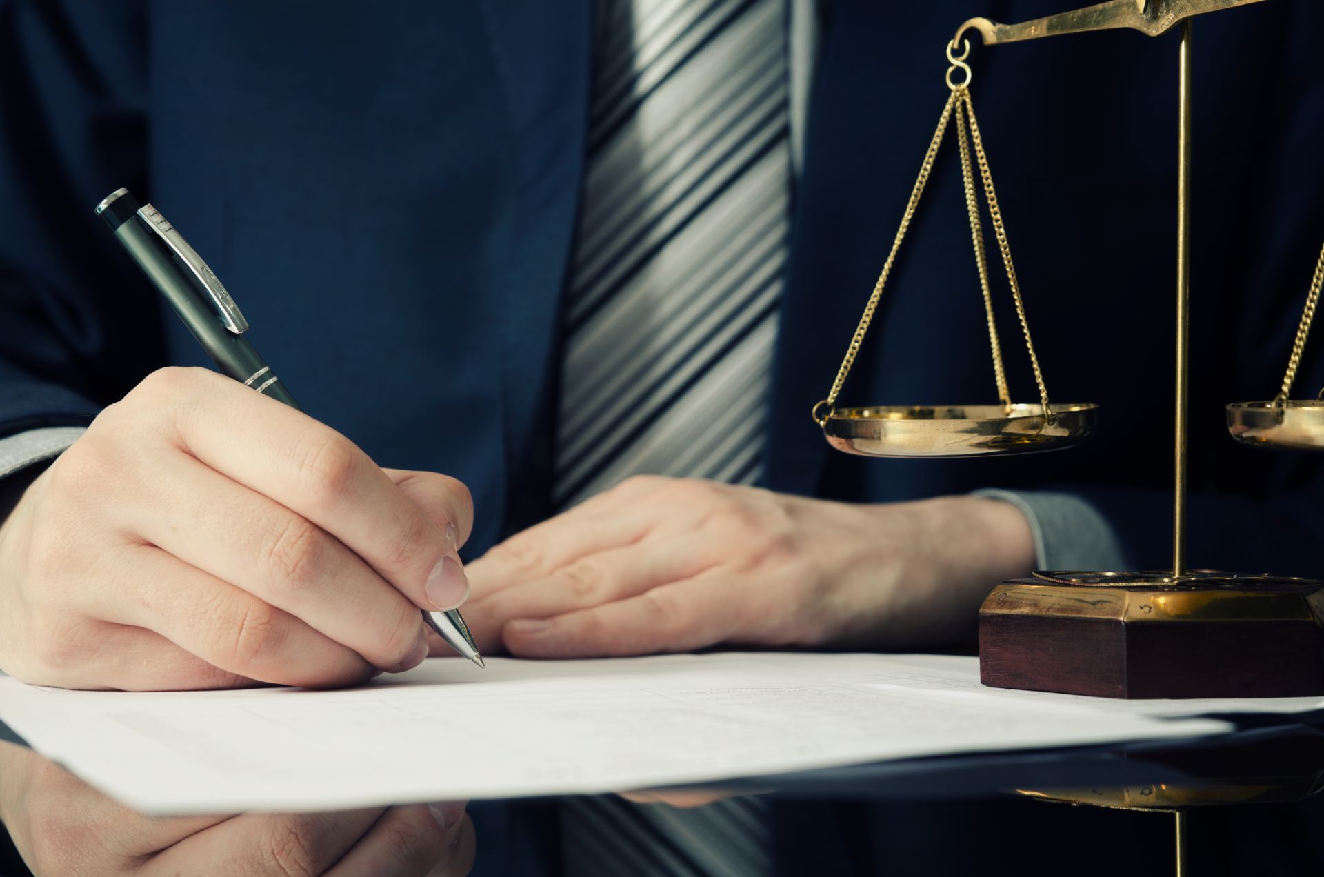 Man signing papers with scales of justice