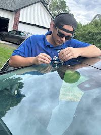 Close-up shot of a technician measuring a minor bullseye rock chip on a vehicle windshield to see if