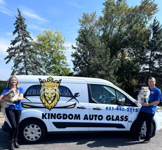 Kingdom Auto Glass van with two people standing beside it outdoors under a blue sky.
