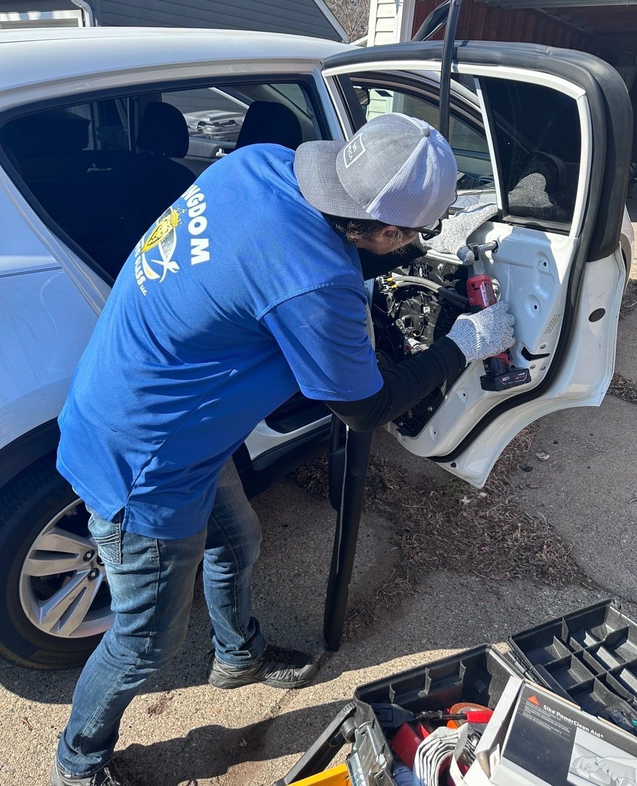 Mechanic in blue shirt inspecting the interior of a white car with the door open.