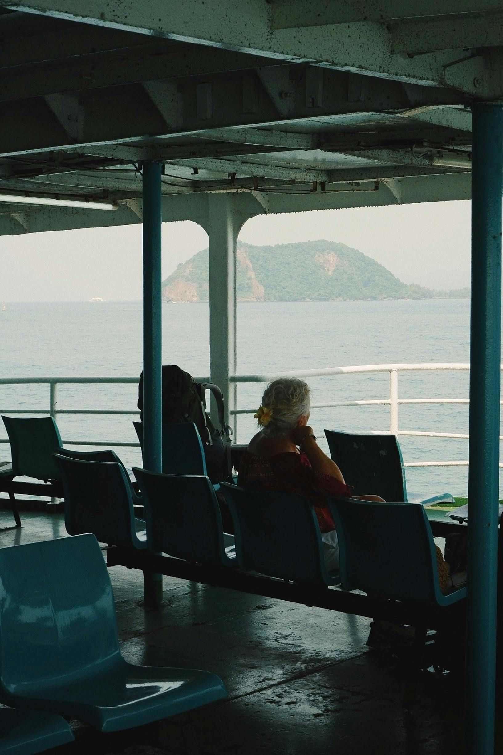 A woman sits on a boat deck looking out over the ocean