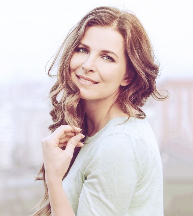 a woman with long hair is smiling and holding her hair