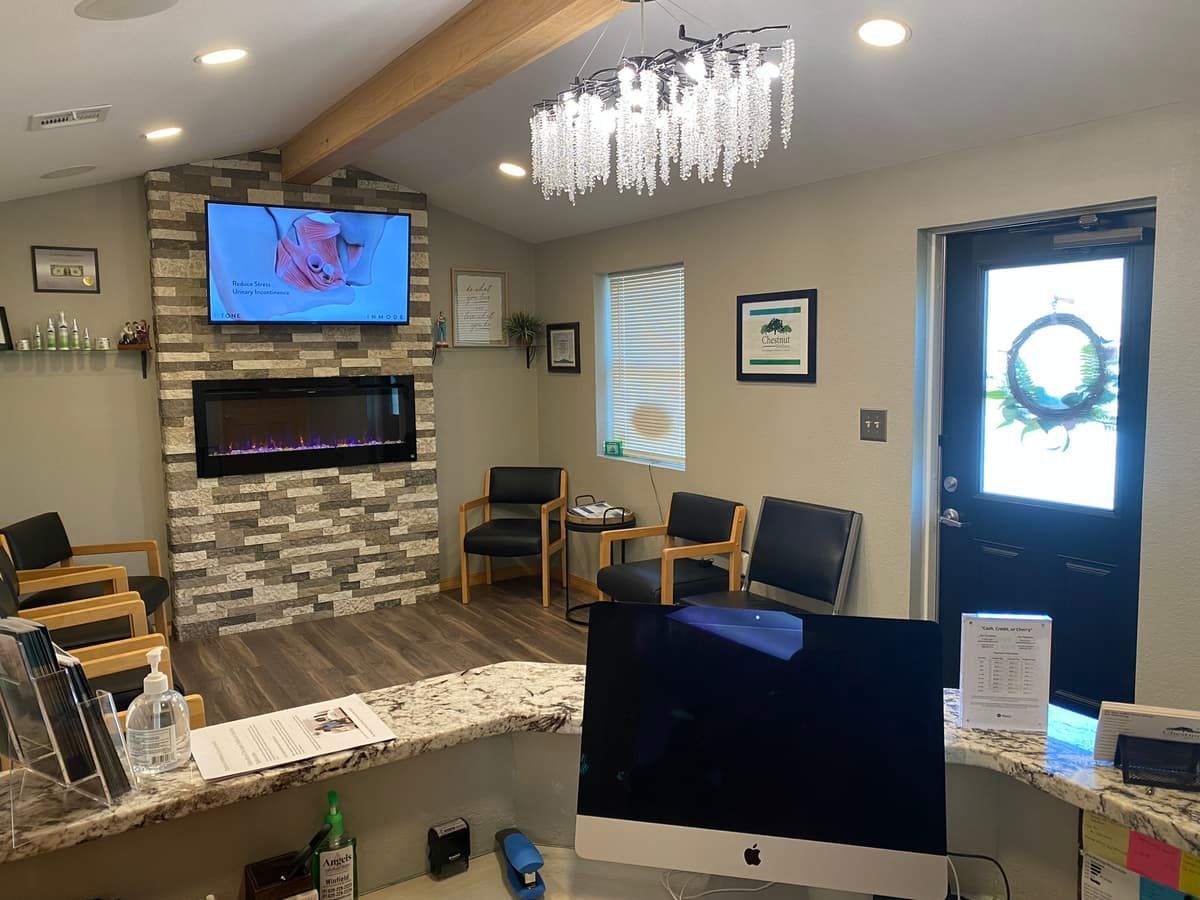 A waiting room with a fireplace , chairs , a computer and a television.