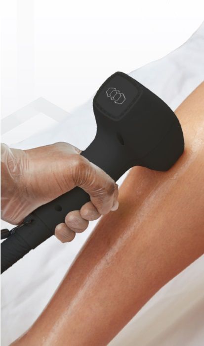 A clinician is using a black hair removal device on a leg
