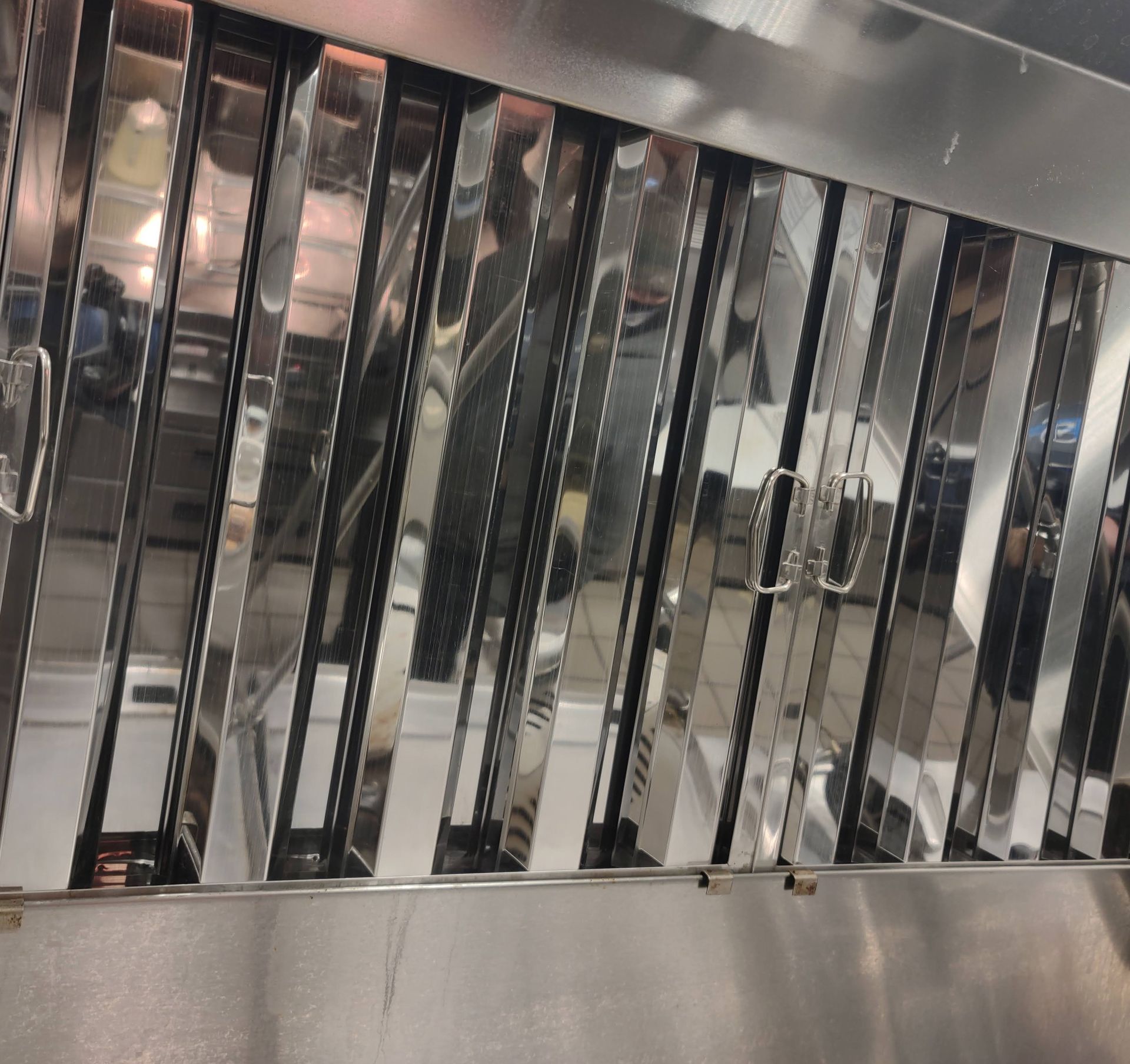 A close up of a stainless steel exhaust hood in a kitchen