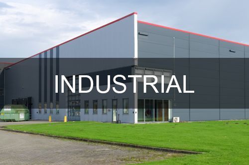 A large industrial building with a lot of grass in front of it.