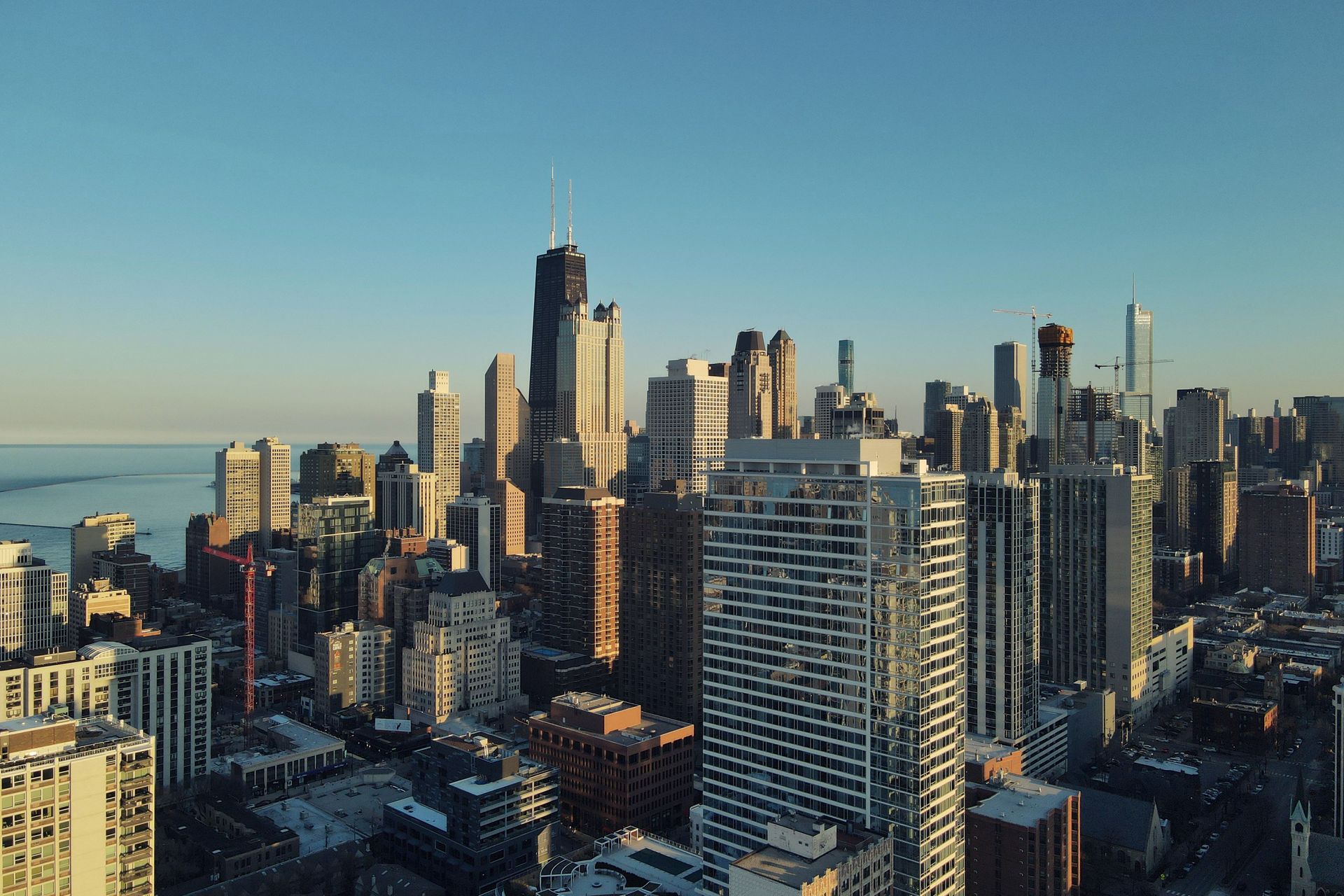 An aerial view of a city skyline at sunset with a lake in the foreground.