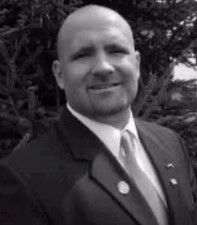 A man in a suit and tie is smiling in a black and white photo.