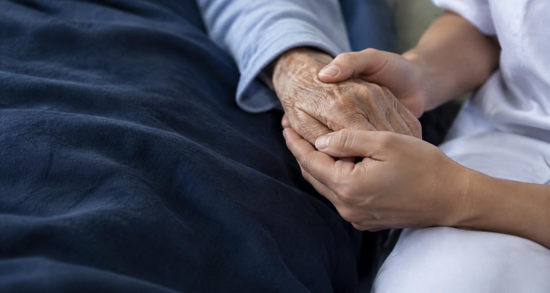 An illustrative care interaction: hands gently holding an older person's hand