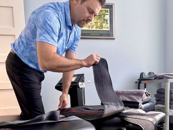 Dr. Matt Murdock, certified nurse practitioner and sports chiropractor, prepares a DOC table for spinal decompression therapy to provide lower back pain relief in his chiropractic clinic