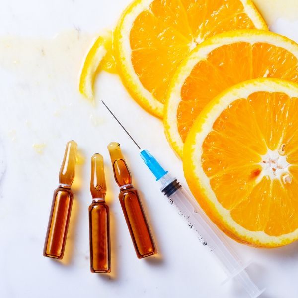 sliced oranges next to a syringe, vitamin injection