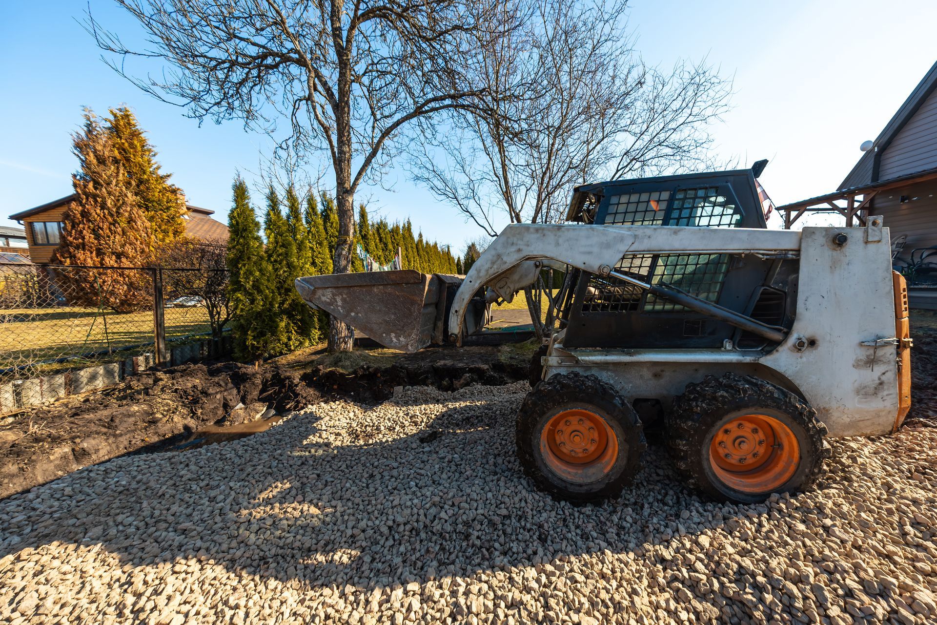 Yellow excavator digging dirt beside a house under construction, with a red tarp and piles of soil nearby. Yellow excavator digging dirt beside a house under construction, with a red tarp and piles of soil nearby.