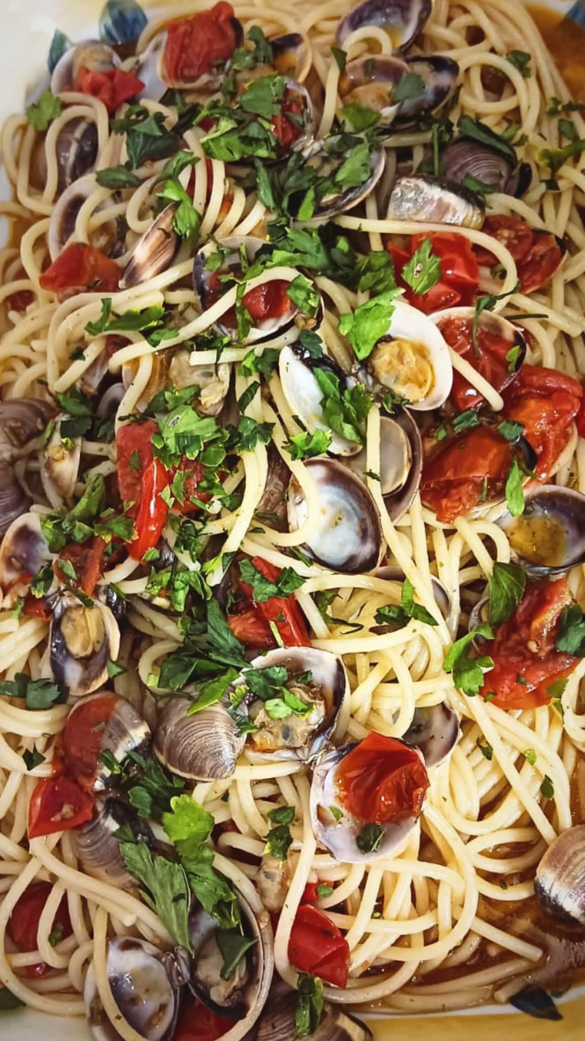 Spaghetti con vongole, pomodorini, prezzemolo e aglio in un primo piano
