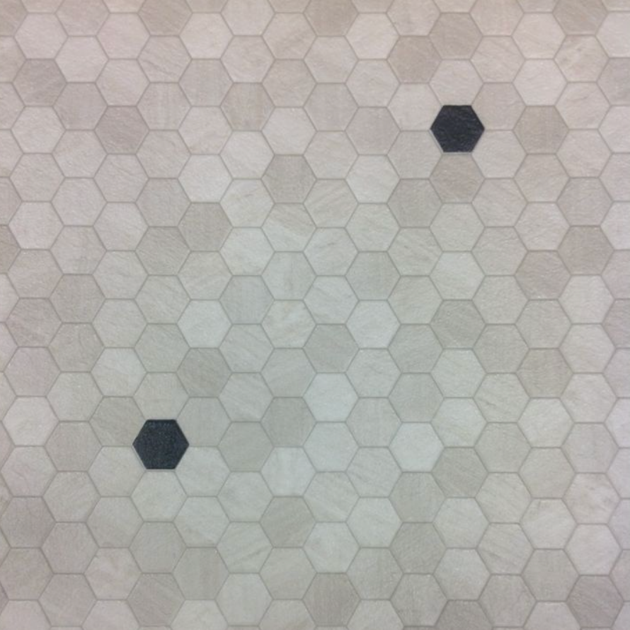 A close up of a honeycomb tile floor with two black circles in the middle.