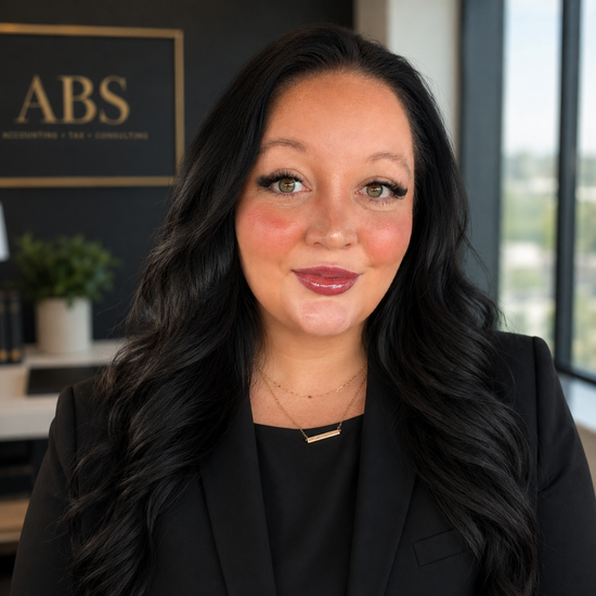 Woman in a black blazer smiling in an office with an ABS sign in the background
