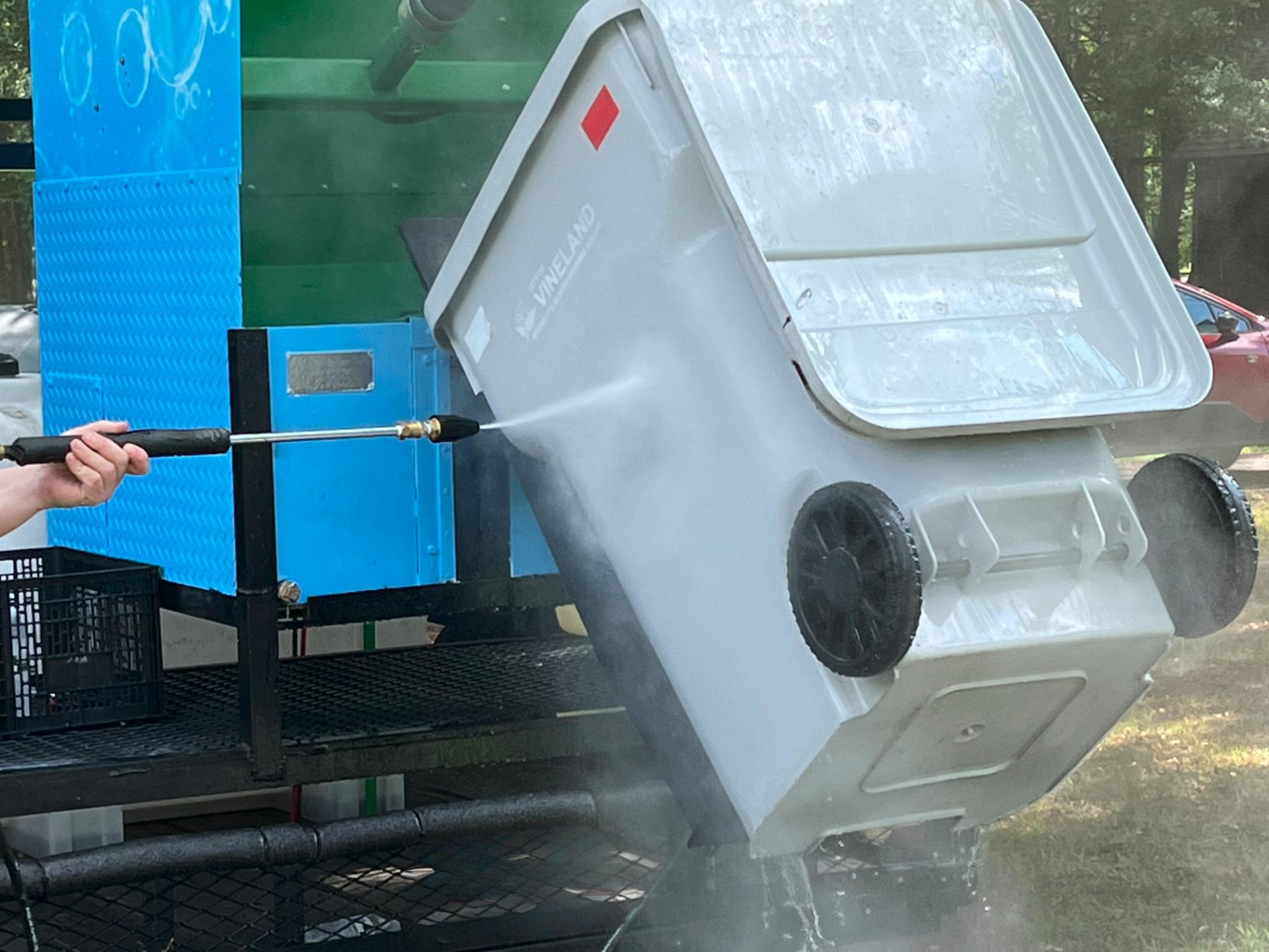 Bin Blitz technician sanitizing a trash bin with a pressure-washer