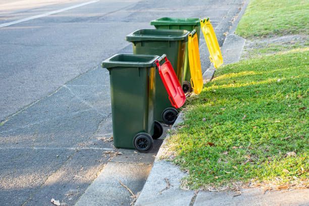 Three trash cans are lined up on the side of the road in Vineland, NJ