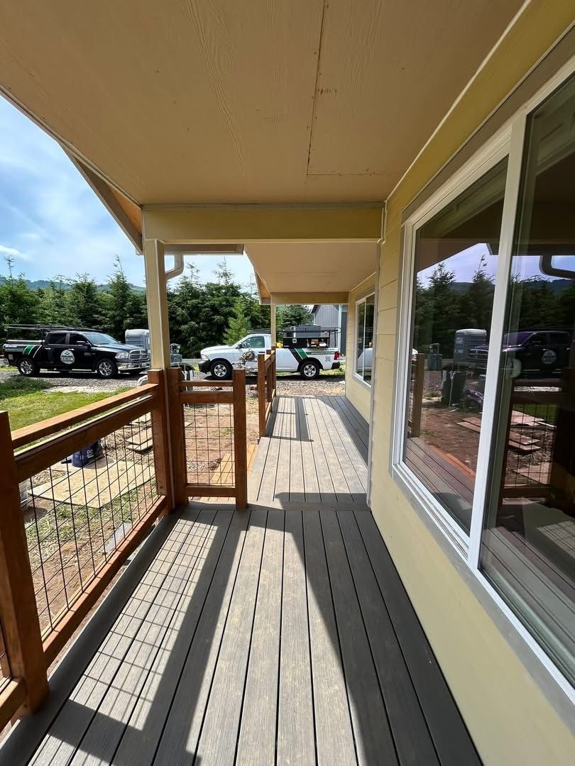 Covered apartment walkway with wooden railing, windows, and parked cars along the street.