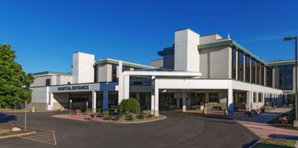 Modern white hospital building with blue glass windows under a clear sky
