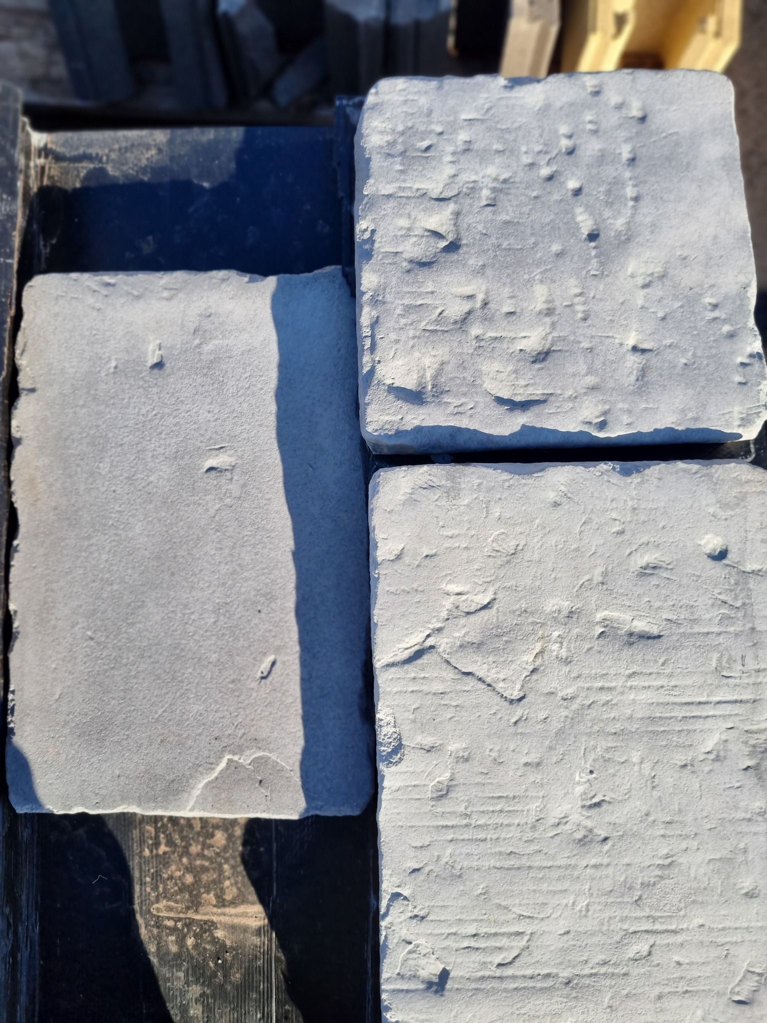 Four Grey Square Pavers With Textured Surfaces Arranged In A Bin — Port Landscape Supplies in Port Macquarie, NSW