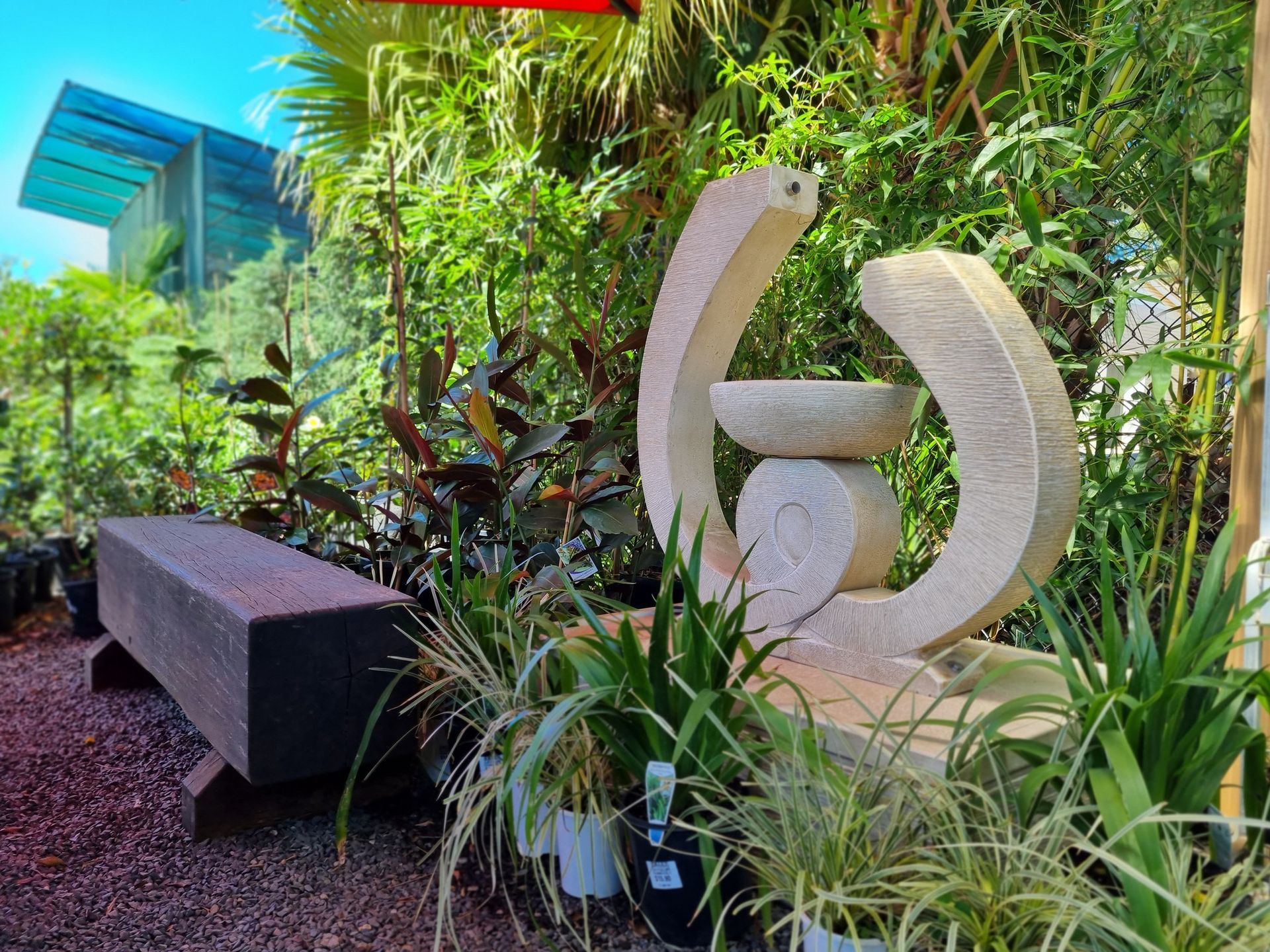 Stone Fountain Sculpture in A Garden with A Bench and Plants — Port Landscape Supplies in Port Macquarie, NSW