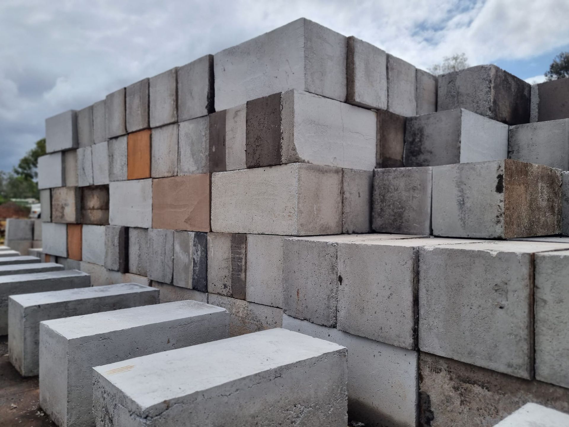 Stack Of Grey and Orange Concrete Blocks Stacked Outdoors — Port Landscape Supplies in Port Macquarie, NSW