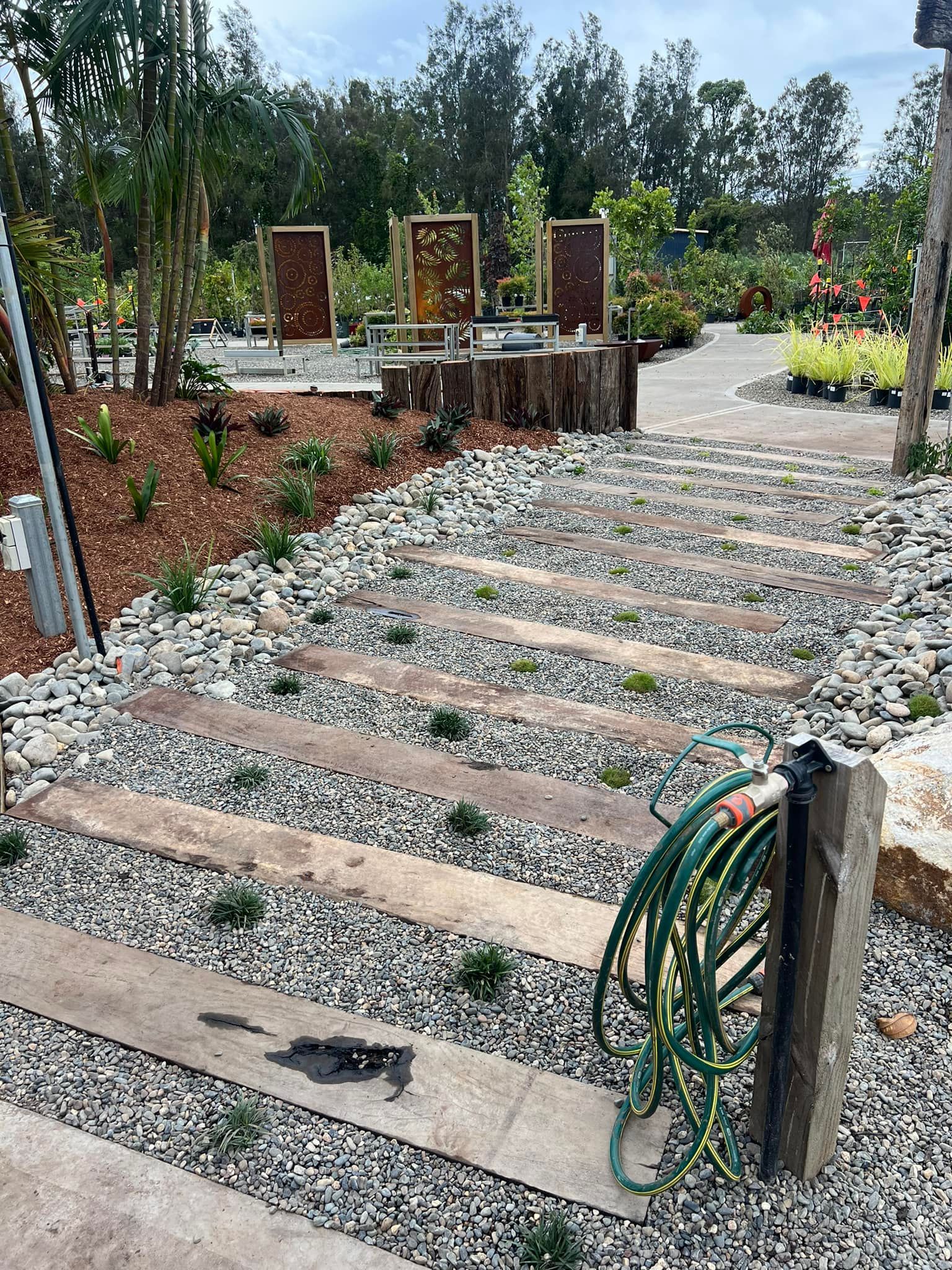 Stone Pathway with Wooden Steps, Surrounded by Pebbles and Greenery — Port Landscape Supplies in Port Macquarie, NSW